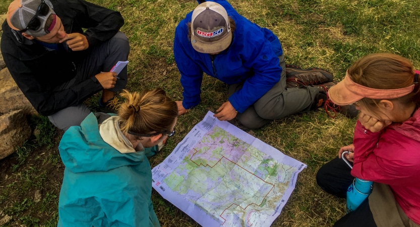 a group of students examine a map that is spread out on the ground